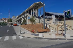 aménagement moderne des abords de la Gare de Béziers avec la nouvelle passerelle piétonne et le jalonnement dynamique du parking EFFIA : l'image montre un espace public optimisé incluant des zones piétonnes, du mobilier urbain et une signalétique indiquant le nombre de places disponibles en temps réel.