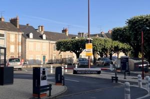 Voie d'accès menant aux barrières de contrôle du parking EFFIA Gare de Châteauroux - Volontaires : l'image montre une signalétique claire au sol et le totem noir indiquant les conditions d'entrée du site.
