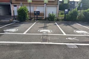 Trois places de parking IRVE signalées par des logos et des panneaux verts.
