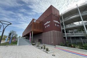Façade moderne du parking EuraPark à Douai : un ouvrage aérien avec habillage métallique brun, rampe d'accès piétonne et parvis aménagé.