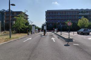 Bornes d'accès et barrières automatiques à l'entrée du parking devant les bâtiments du site.