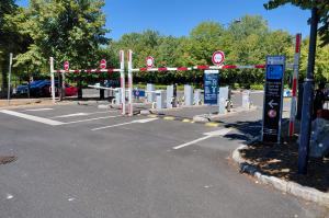 Voies d'accès et de sortie du parking relais équipées de barrières automatiques et du panneau d'information tarifaire.