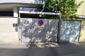 Entrée d'un parking couvert pour abonnés avec des portes de garage et des panneaux de signalisation.