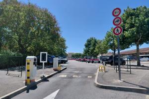 Accès au parking extérieur équipé de bornes de distribution de tickets, de barrières levantes et de la signalisation réglementaire.