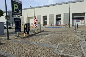 Entrée du parking courte durée avec borne de distribution de tickets et panneau d'affichage des tarifs.