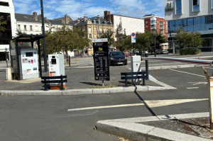 Accès au parking avec totem tarifaire, borne d'entrée à barrière et caisse automatique couverte.