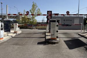 Voies d'entrée et de sortie avec bornes de contrôle, barrières automatiques et local d'accueil.