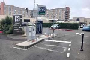Borne de contrôle d'accès, barrière automatique et panneaux d'information à l'entrée du parking P1 de l'hôpital.