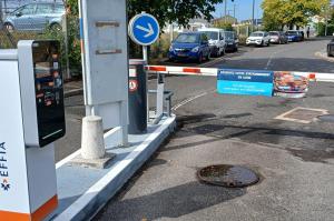 Borne d'accès et barrière automatique à l'entrée du parking extérieur.