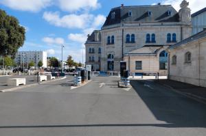 Accès au parking avec barrières automatiques et bornes de paiement devant le bâtiment historique de la gare.