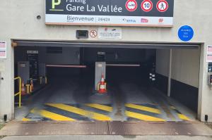 Entrée du parking EFFIA Gare La Vallée avec panneau d'affichage des consignes, limite de hauteur à 1,90 m et bornes d'accès.
