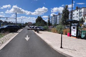 Voie de sortie du parking avec barrière automatique, borne de validation et caisse automatique abritée sur le côté.