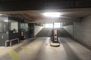 Rampes d'accès et de sortie d'un parking couert équipées de bornes de péage et d'un poste de contrôle.