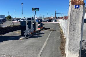 Voie d'accès au parking équipée de bornes de contrôle et d'un panneau d'affichage indiquant les places libres.