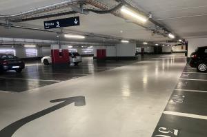 Emplacements de stationnement numérotés au sol au niveau 3 d'un parking couvert, avec signalisation directionnelle.