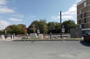 Emplacements de stationnement extérieurs équipés de bornes de recharge pour véhicules électriques avec panneaux d'information.