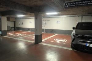 Emplacements au sol rouge réservés à la recharge des véhicules électriques dans le parking souterrain.