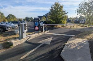 Zone de sortie équipée d'une borne de paiement, d'un panneau de signalisation et d'une barrière automatique.