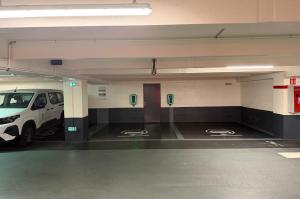 Emplacements réservés à la recharge des véhicules électriques équipés de bornes murales rétroéclairées en vert.