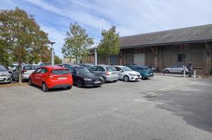 Rangée de voitures stationnées sur le parking devant un long bâtiment.