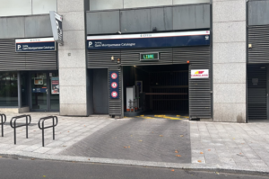 Vue extérieure montrant l'accès à la gare ou au parking sous un bâtiment.