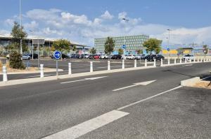 Voies d'accès d'un parking extérieur avec barrières et bornes de contrôle.
