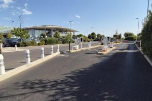 Voies d'entrée d'un parking extérieur équipées de barrières et de bornes.