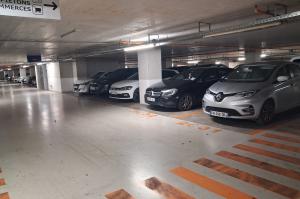 Rangée de voitures garées dans un parking souterrain avec marquage au sol.