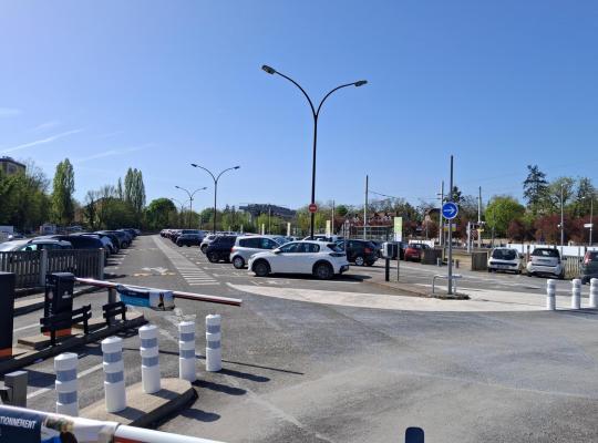 vue rapprochée de l'entrée d'un parking géré par EFFIA avec des bornes de contrôle et des barrières automatiques: le visuel met en avant la possibilité de réserver sa place de stationnement en ligne pour un départ serein.