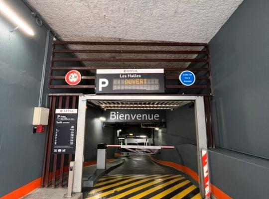 Vue rapprochée de l'entrée République du parking EFFIA Diderot : l'image met en valeur le grand totem signalétique noir, l'accès sécurisé pour les véhicules et l'intégration d'un magasin d'alimentation bio "La Vie Claire" au rez-de-chaussée.