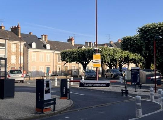 Voie d'accès menant aux barrières de contrôle du parking EFFIA Gare de Châteauroux - Volontaires : l'image montre une signalétique claire au sol et le totem noir indiquant les conditions d'entrée du site.