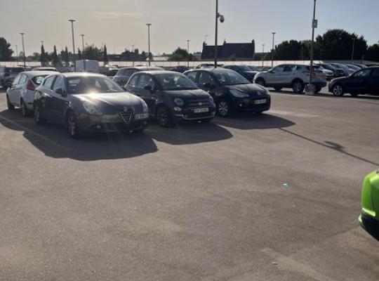 Perspective de la rue pavée menant à l'entrée du parking EFFIA de l'Hôtel de Ville de Châteauroux : une signalétique urbaine moderne s'intègre parfaitement dans cet environnement arboré pour orienter les automobilistes en centre-ville.