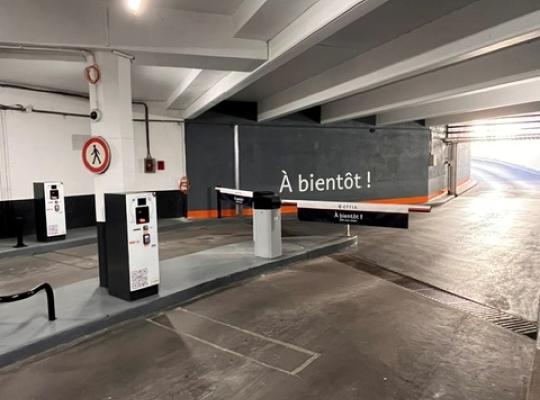 Rampe d'accès intérieure moderne et sécurisée reliant les niveaux du parking couvert EFFIA Diderot : un aménagement fonctionnel doté d'une signalétique directionnelle (flèches au sol) et de barrières de protection pour les piétons.