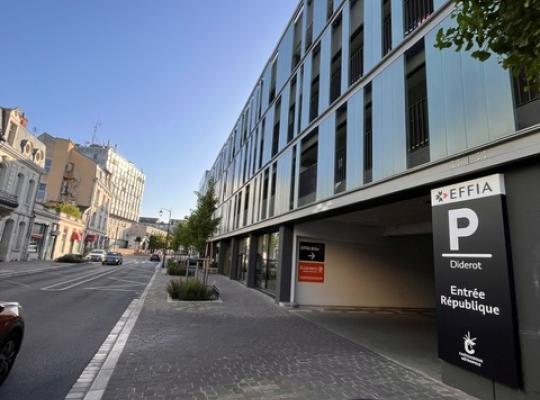 Vue en perspective de l'entrée République du parking EFFIA Diderot le long d'une artère urbaine : le grand totem noir de la marque guide efficacement les automobilistes vers l'accès couvert du site sécurisé.