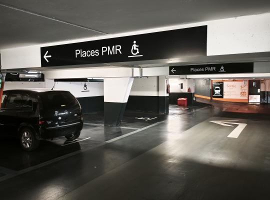 places de stationnement PMR signalées par de grands panneaux noirs au plafond.