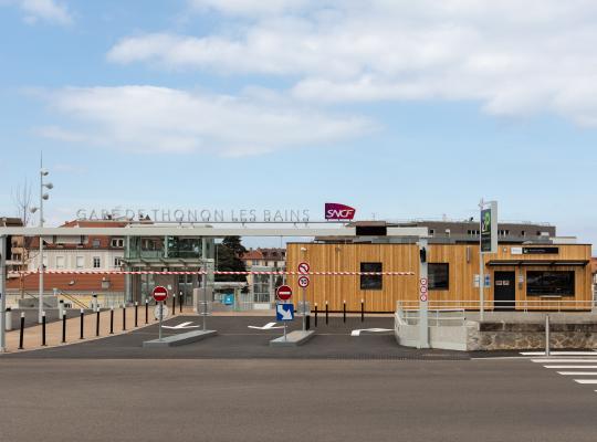 Entrée principale et bâtiment d'accueil en bois du parking EFFIA Gare de Thonon-les-Bains, avec portique d'accès et enseigne SNCF.