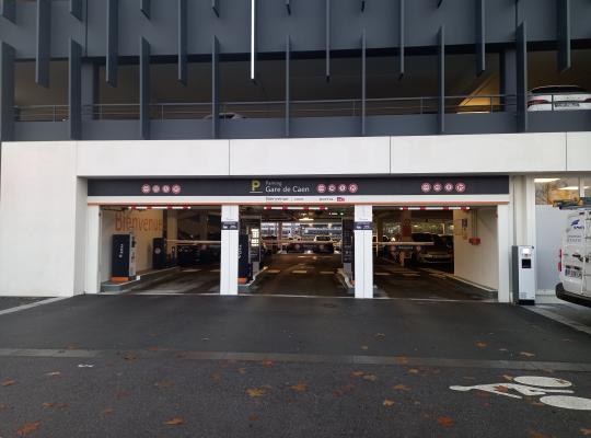 Entrée du parking EFFIA de la gare de Caen : accès multi-voies par barrière avec bornes de tickets sous la structure moderne du bâtiment.
