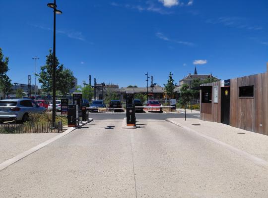 Vue d'une allée de circulation centrale au sein du parking extérieur EFFIA : un aménagement paysager propre et aéré doté de places de stationnement délimitées et d'arbres d'alignement pour le confort des usagers.