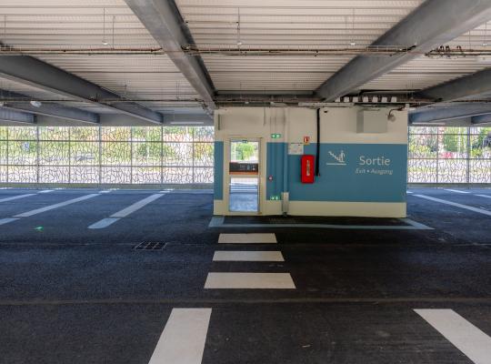 Intérieur du parking couvert EFFIA Gare d'Esbly : places numérotées, signalétique "Sortie" bien visible et sas piéton sécurisé avec réseau tressé ajouré.
