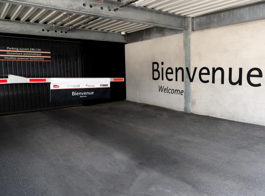 Accès intérieur sécurisé du parking EFFIA Gare de Cormeilles-en-Parisis : porte automatique et barrière de contrôle avec message d'accueil pour un stationnement ouvert 24h/24.
