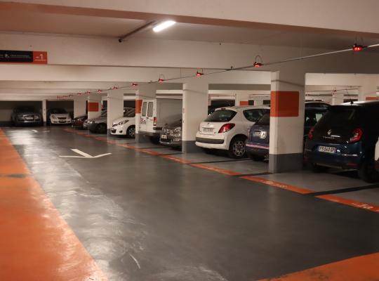 Intérieur lumineux du parking souterrain Jean Jaurès (niveau -1) : places de stationnement délimitées, marquage au sol orange et détecteurs de présence lumineux pour se garer facilement.