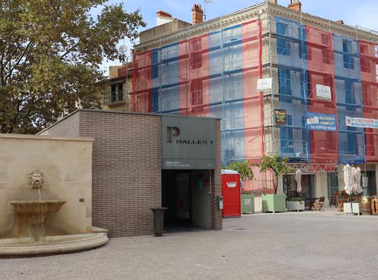 Accès piéton moderne du parking EFFIA Halles 1, situé sur une place pavée à proximité immédiate des commerces, des terrasses et des bâtiments historiques.