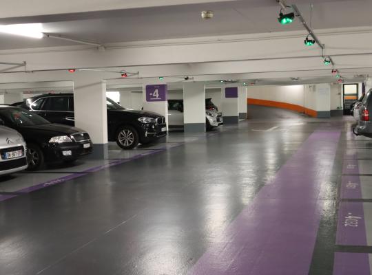 Vue intérieure du niveau -4 du parking EFFIA Halles 1 : places délimitées avec code couleur violet, éclairage LED performant et capteurs lumineux de guidage à la place.