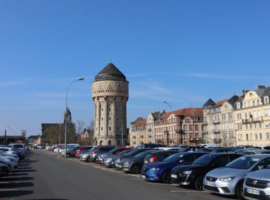 Grand parking extérieur EFFIA de la Gare de Metz : nombreuses places de stationnement avec vue sur le Château d'eau historique et les façades de la ville.