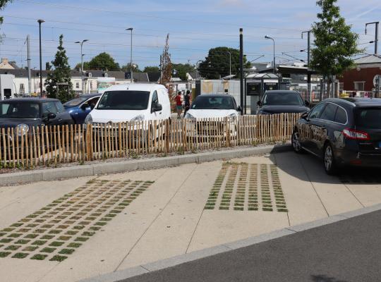 Emplacements de stationnement aménagés du parking EFFIA Gare de Vannes, avec dalles végétalisées et bordures en clôture bois.