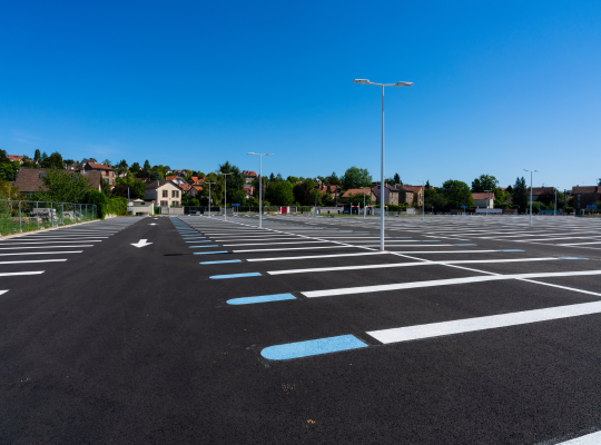 Le grand parking extérieur EFFIA de la Gare d’Esbly : vaste zone de stationnement goudronnée avec marquages au sol clairs et éclairage public.