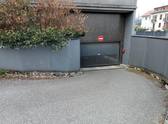 Rampes d'accès et portail automatique de sortie d'un parking souterrain sécurisé, surmonté d'un panneau sens interdit.