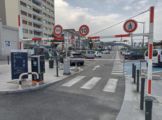 Accès principal du parking EFFIA Gare d'Aix-les-Bains : borne de distribution, portique de limitation de hauteur à 1,90 m et panneau des tarifs.