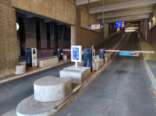 Barrières automatiques et bornes d'accès à l'entrée couverte du parking.