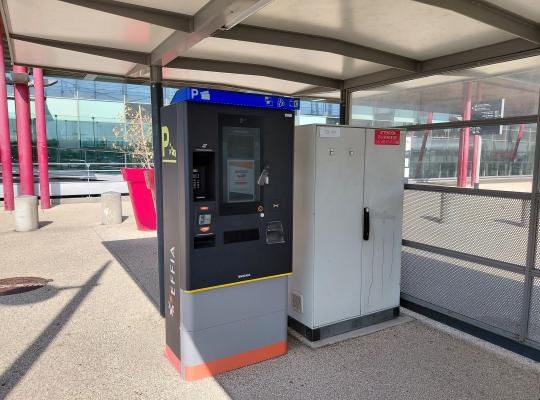 Caisse automatique de paiement EFFIA installée sous un abri vitré près du parvis de la gare.